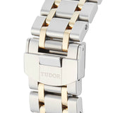 Close-up of a silver and gold watch band with TUDOR engraved.