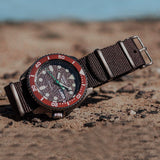 Close-up of a wristwatch with a brown band on sand.
